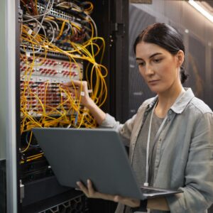 Person holding a laptop while working with cables